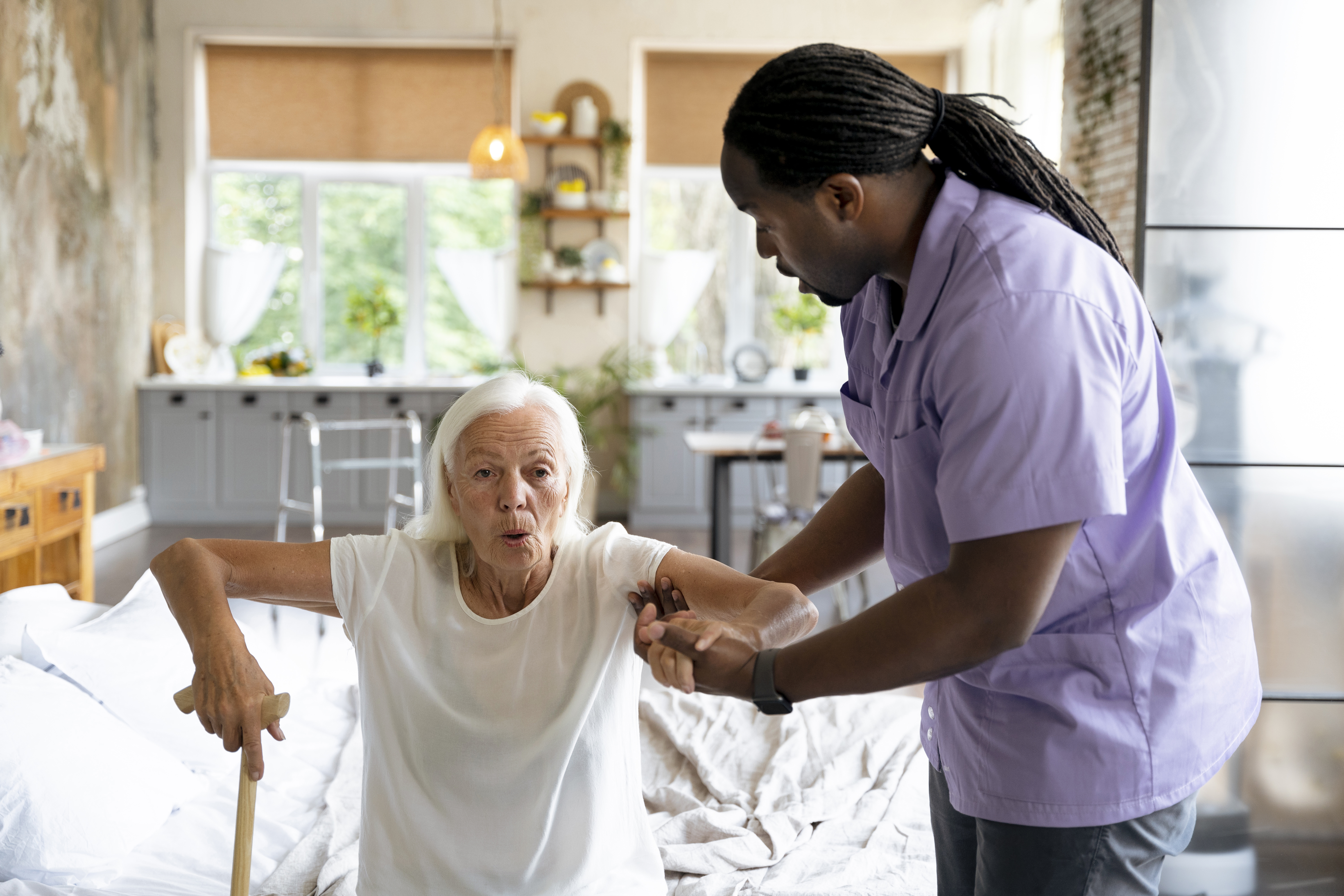 Caregiver helping an older adult stand up from a chair